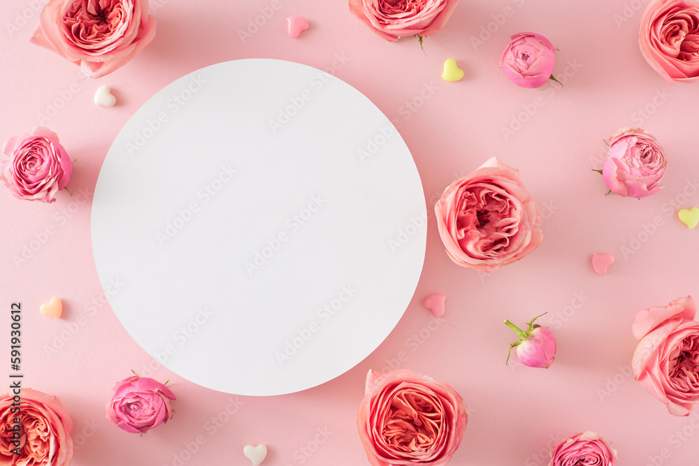 Women's Day atmosphere concept. Creative layout made of empty circle and natural flowers pink rose buds and small hearts on isolated pastel pink background. Flat lay with blank space