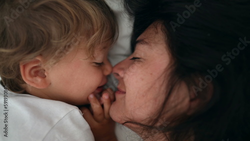Mother and child love and care laying in bed. Lifestyle moment of mom and son eskimo kiss during weekend