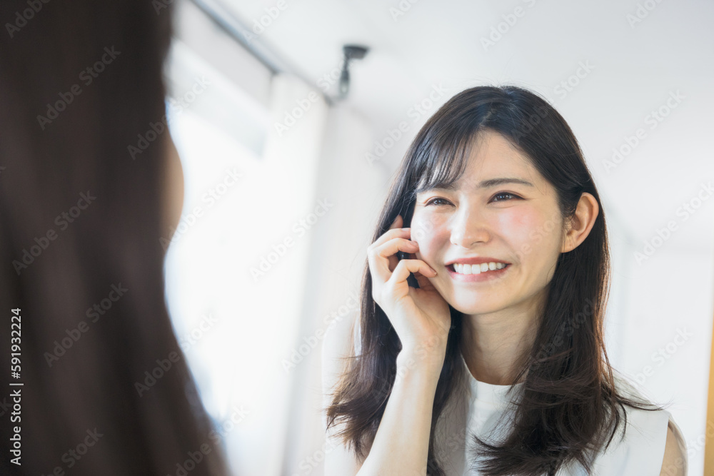 鏡に映る自分の顔をみて肌の状態の良さに嬉しくなり笑顔になる30代の女性(ビューティーイメージ) 鏡に映る自分の顔をみて肌の状態の良さに嬉しくなり笑顔になる30代の女性(ビューティーイメージ)