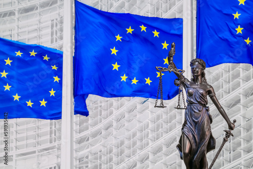 Themis and Europien Union flags on blurred buckground, shallow depth of field, focus on Themis statue. European Union law and jurisprudence photo