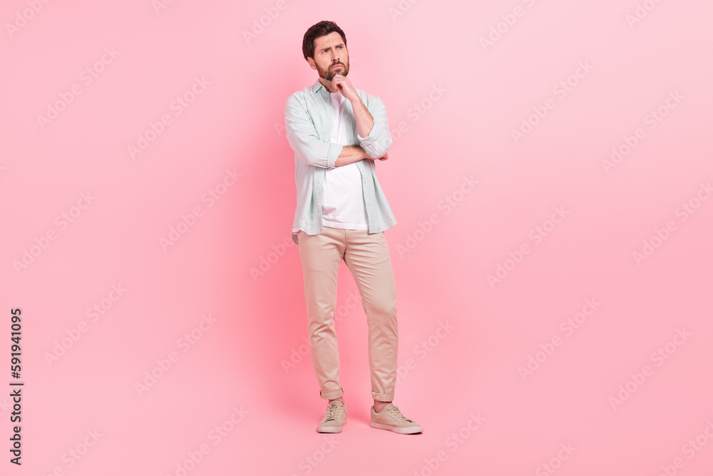 Full length photo of nice young male deep minded pensive thoughtful dressed stylish blue garment isolated on pink color background Full length photo of nice young male deep minded pensive thoughtful dressed stylish blue garment isolated on pink color background