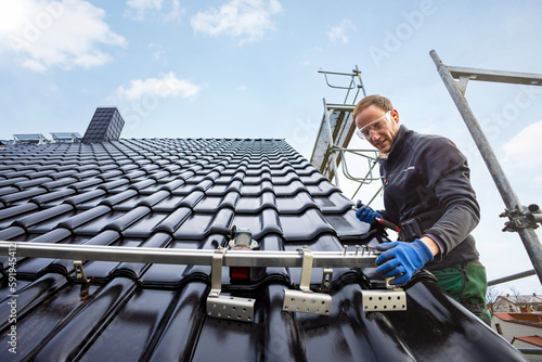 Bild auf Leinwand Craftsman installing the solar panel mounting system on a roof