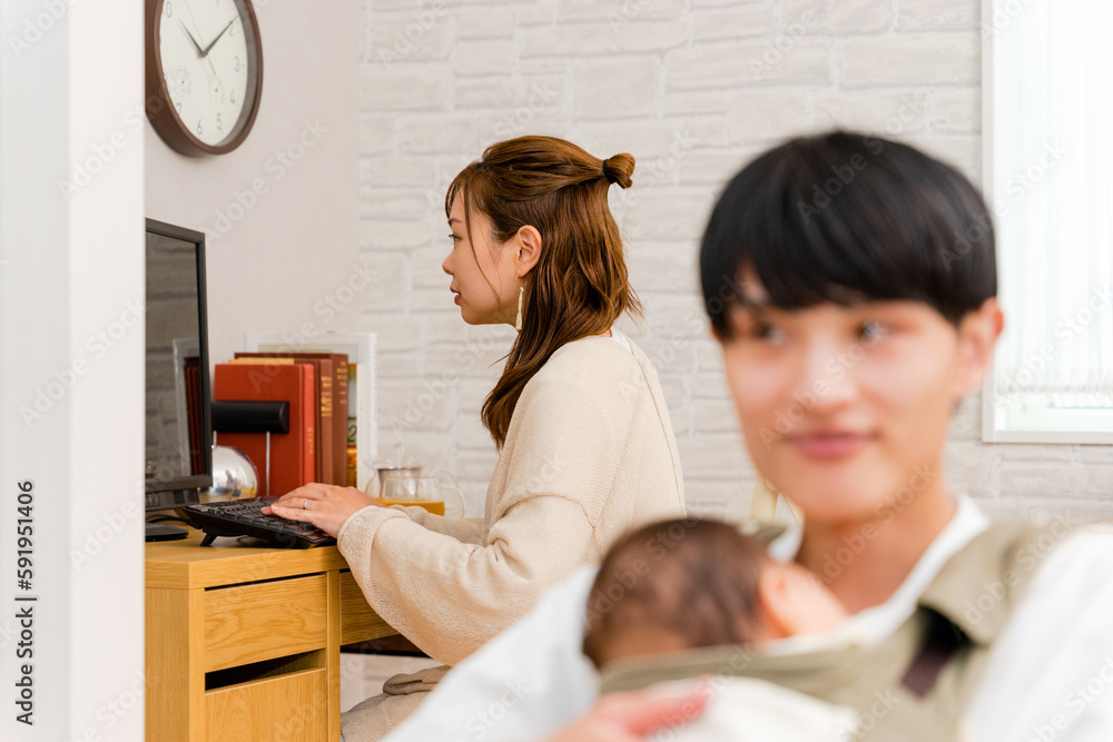 テレワークで働く母親の女性と育児をする父親の男性 テレワークで働く母親の女性と育児をする父親の男性