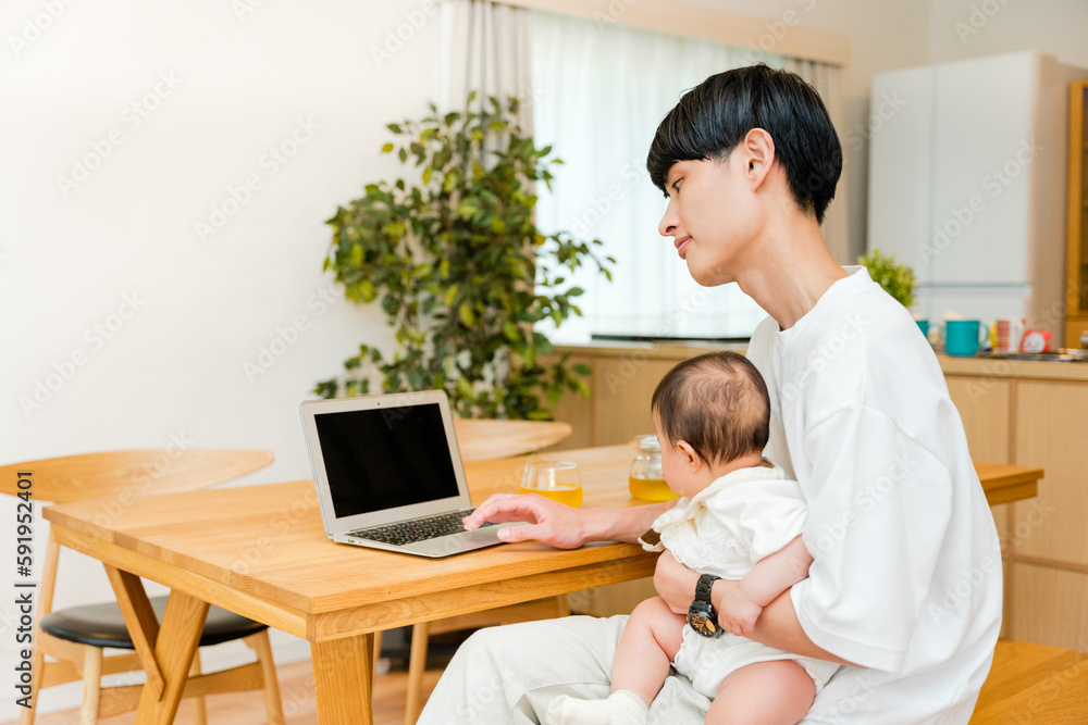 Obraz premium リビングで0歳児の赤ちゃんを抱っこしながら仕事をする父親の男性