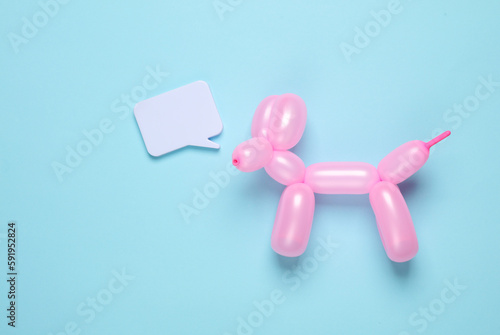Pink balloon in the shape of dog with speech bubble on blue background. Top view