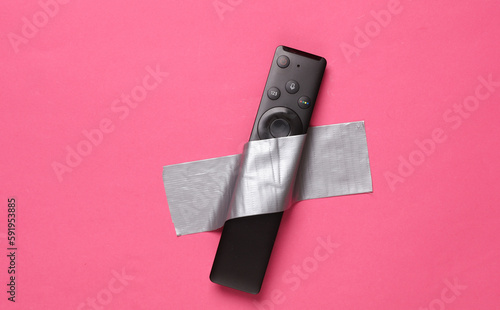 Photos Tv remote fixed with adhesive tape on a pink background