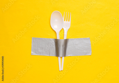 Canvastavla Plastic fork and spoon fixed with adhesive tape on yellow background