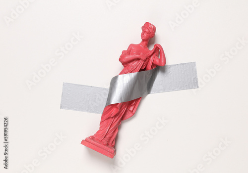 Antique statue of venus fixed with adhesive tape on white background. Conceptual pop, contemporary art, minimalist still life