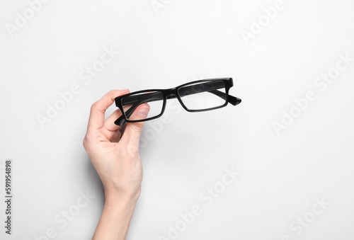 Women's hand hold eyeglasses on a gray background. Vision correction