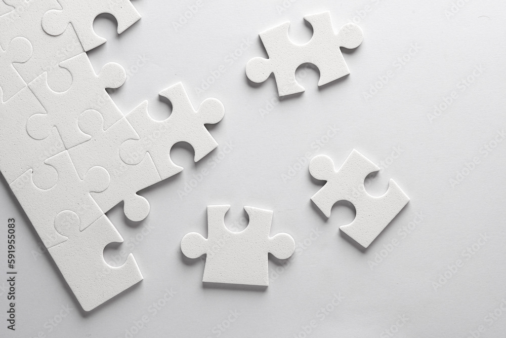 Fototapeta premium White jigsaw puzzle pieces on a gray background.