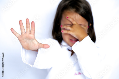 Criança com a mão no rosto sinalizando pare com outramão. photo