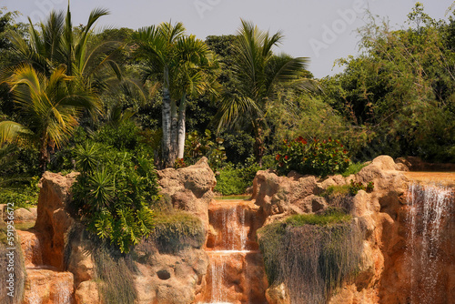 Tropical paradise, palm trees, waterfalls, rocks and blue sky. An idyllic summer vacation