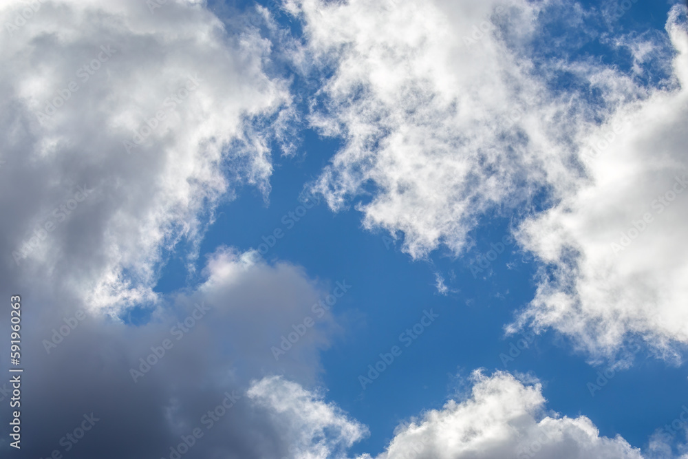 Clear cloudy sky on sunny winter day. Cumulus, blue window in cloudy sky. Bottom-up view. Cloudy sky on sunny winter day Clear cloudy sky on sunny winter day. Cumulus, blue window in cloudy sky. Bottom-up view. Cloudy sky on sunny winter day