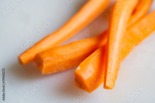 Sliced raw carrots on a white cutting board. Cooking carrots.