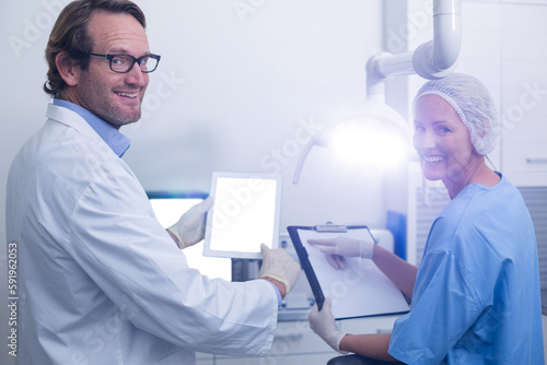 Portrait of dentist and dental assistant working on digital tablet