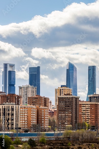 Skyscrapers located in the city of Madrid  Spain  during a cloudy day  rising above the residential buildings. Vertical shot.