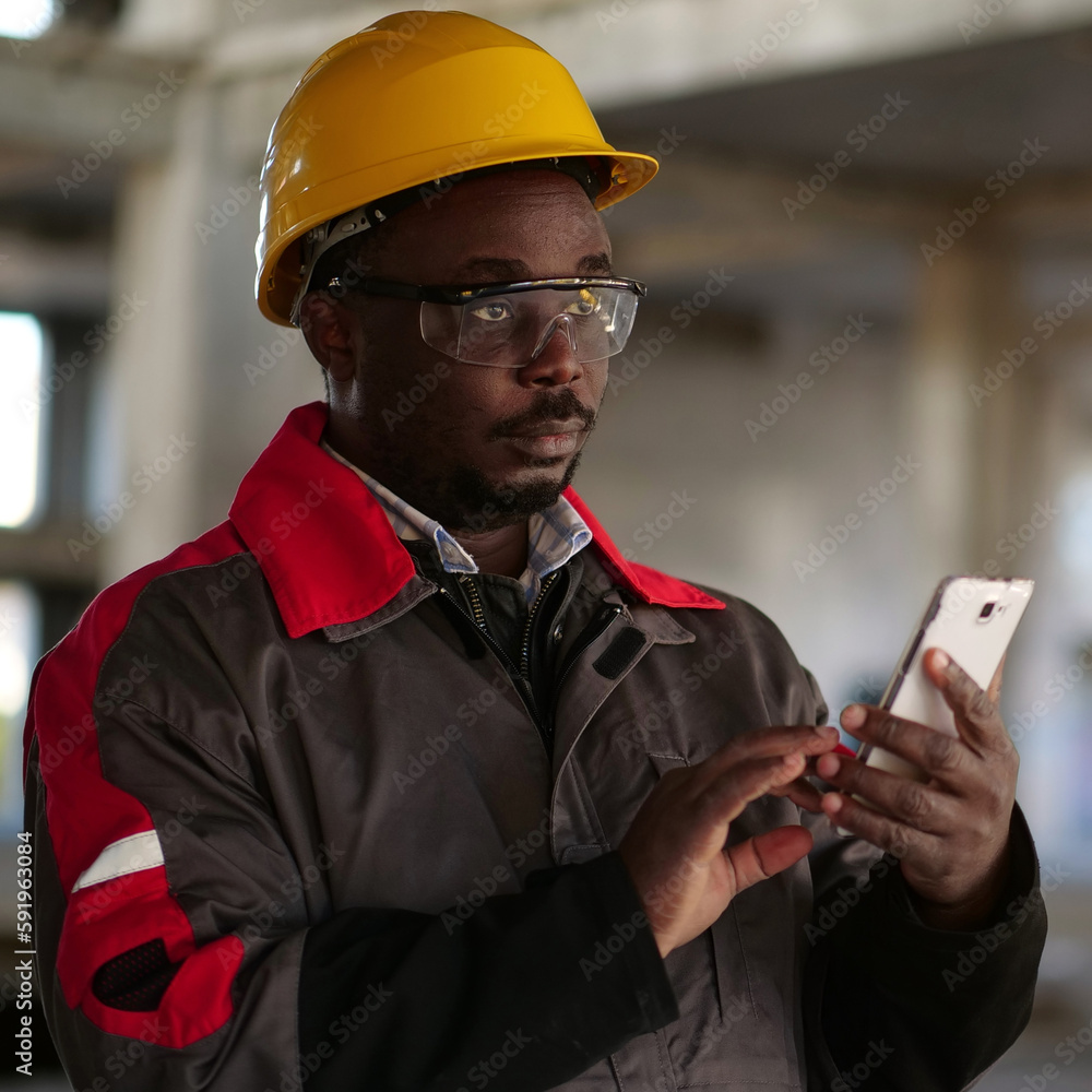 African american workman with smartphone at construction site African american workman with smartphone at construction site