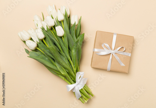 White tulip bouquet and gift box on color background  top view