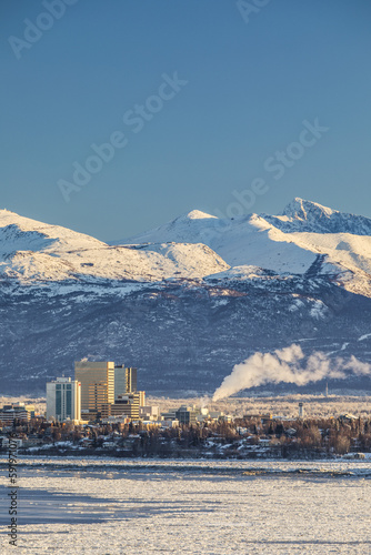 View Of Downtown Anchorage In Winter And The Snow-Capped Chugach Mountains Beyond Seen From Point Mackenzie, The Skies In The Background Clear And Bright, Sea Ice Covering Cook Inlet In The Foreground photo