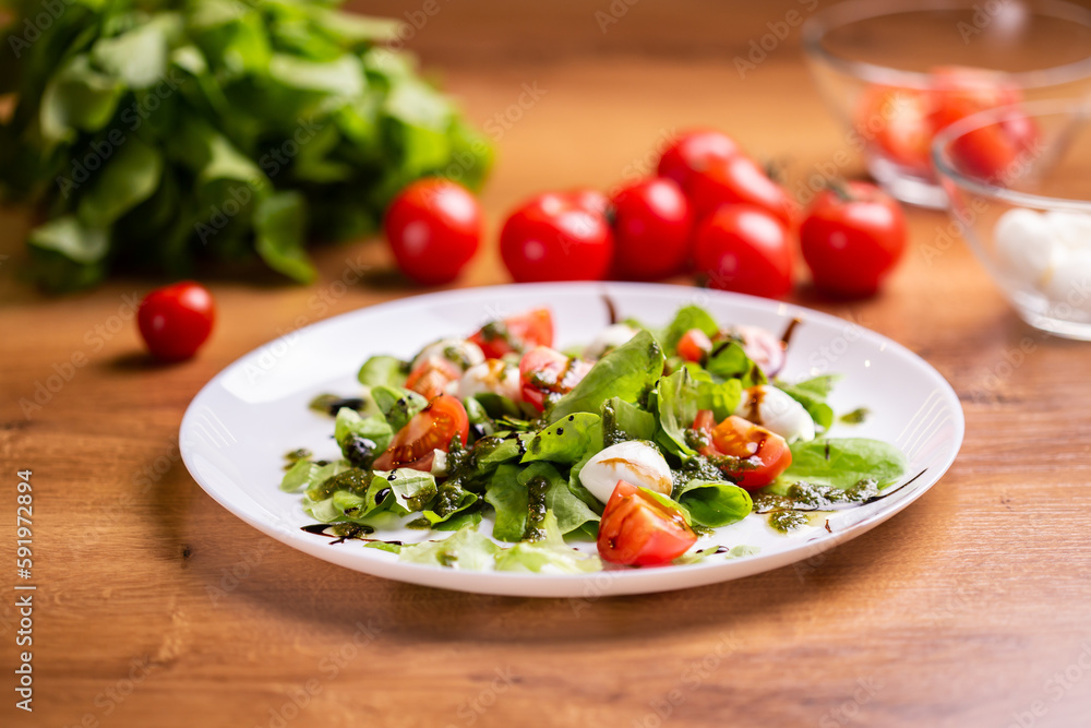 Plate of healthy classic close-up caprese salad with mozzarella cheese tomatoes and basil in kitchen - italian cuisine