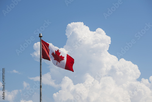 A Canada flag flying in a blue sky with cloud; Prince Edward Island, Canada