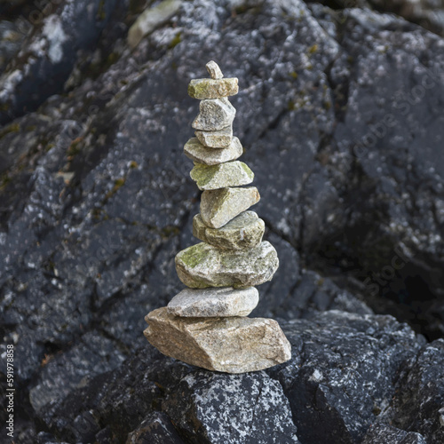 A pile of rocks balancing on a black boulder on Tonquin Beach, Vancouver Island; British Columbia, Canada photo
