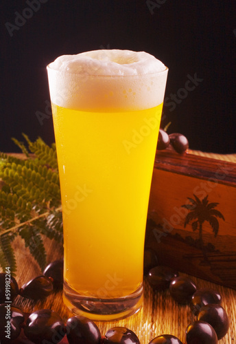 A Tall Foaming Pint Of Beer In A Tiki Bar Setting. photo