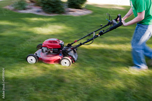 Teenage boy quickly mows a lawn; Elkhorn, Nebraska, United States of America photo
