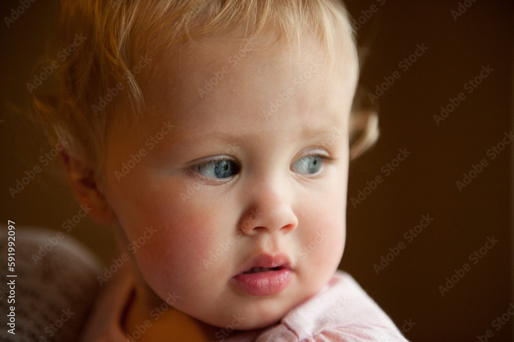 Close-up portrait of a baby girl with blond curls and blue eyes; Lincoln, Nebraska, United States of America Close-up portrait of a baby girl with blond curls and blue eyes; Lincoln, Nebraska, United States of America