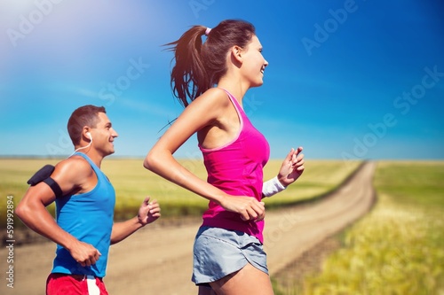 Sporty young happy couple run together outdoors.
