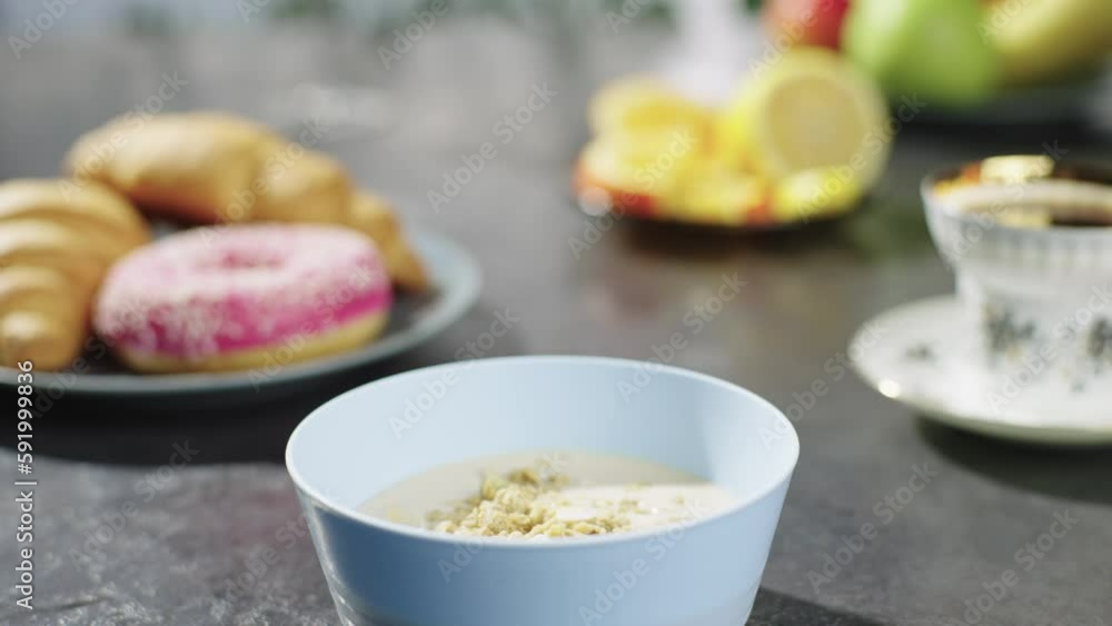 Pouring muesli and granola into a children's plate. Tasty and healthy breakfast with fruit at home. High quality 4k footage Pouring muesli and granola into a children's plate. Tasty and healthy breakfast with fruit at home. High quality 4k footage