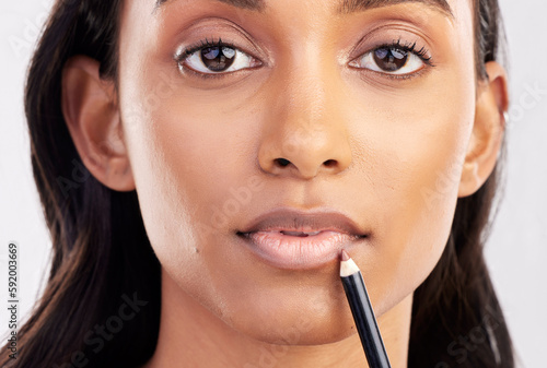 Woman, face closeup and portrait with lip liner makeup, beauty and cosmetic product on studio background. Indian female, cosmetics pencil for lips and lipstick with healthy skin and cosmetology