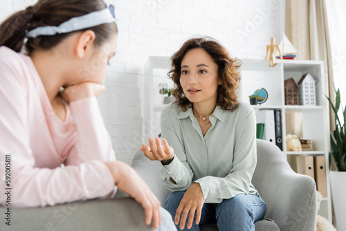 Psychologist talking to blurred preteen kid in consulting room.