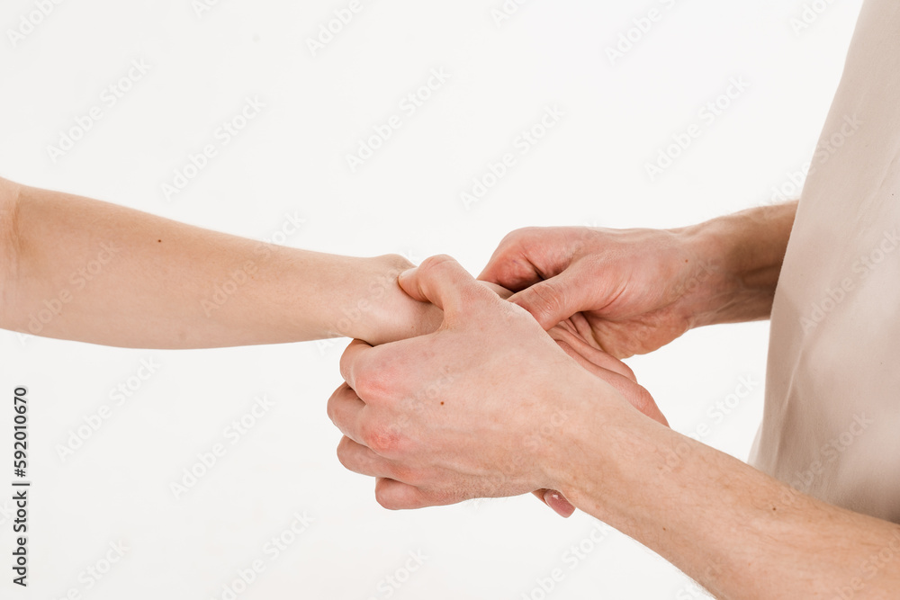 Fototapeta premium Examination of the wrist joint for hygroma, mobilization of the joint. Traumatology. Orthopedist traumatologist examines wrist joint injury of girl and prescribes treatment on white background.