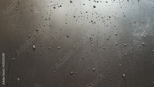 Water drops on a black plastic. Surface with wet background. Abstract texture and pattern full of water. Raindrops of rain for overlaying on window with partial focus. Concept of autumn weather