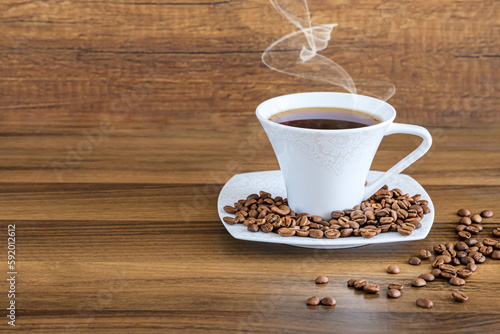 Cup of coffee with beans, coffee beans and a cup of hot drink on brown wooden background. 