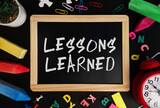 Wooden board with Lessons Learned text on a background of various colorful subjects