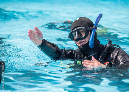 Scuba dive instructor teaching and explaining to students the regulator retrieval skill in the pool