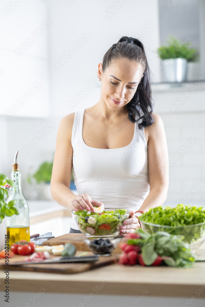 A beautiful brunette prepares a healthy spring leaf salad with various ingredients A beautiful brunette prepares a healthy spring leaf salad with various ingredients