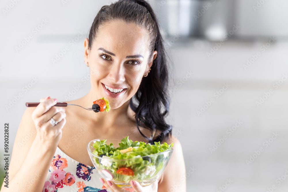 Healthy lifestyle young woman eating lettuce salad. Young brunette eating healthy food in her kitchen Healthy lifestyle young woman eating lettuce salad. Young brunette eating healthy food in her kitchen