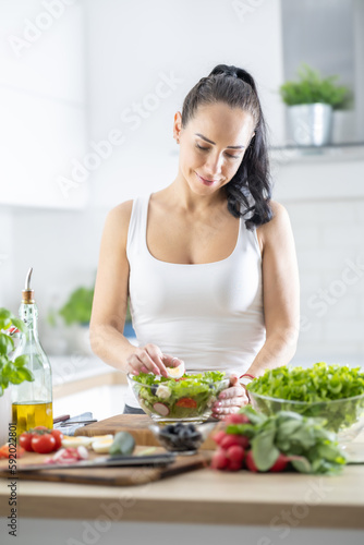 A beautiful brunette prepares a healthy spring leaf salad with various ingredients