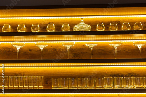 Glasses of wine. Glasses hanging above the bar in restaurant. Empty glasses for wine. Wine and martini glasses in shelf above bar rack in restaurant. night life