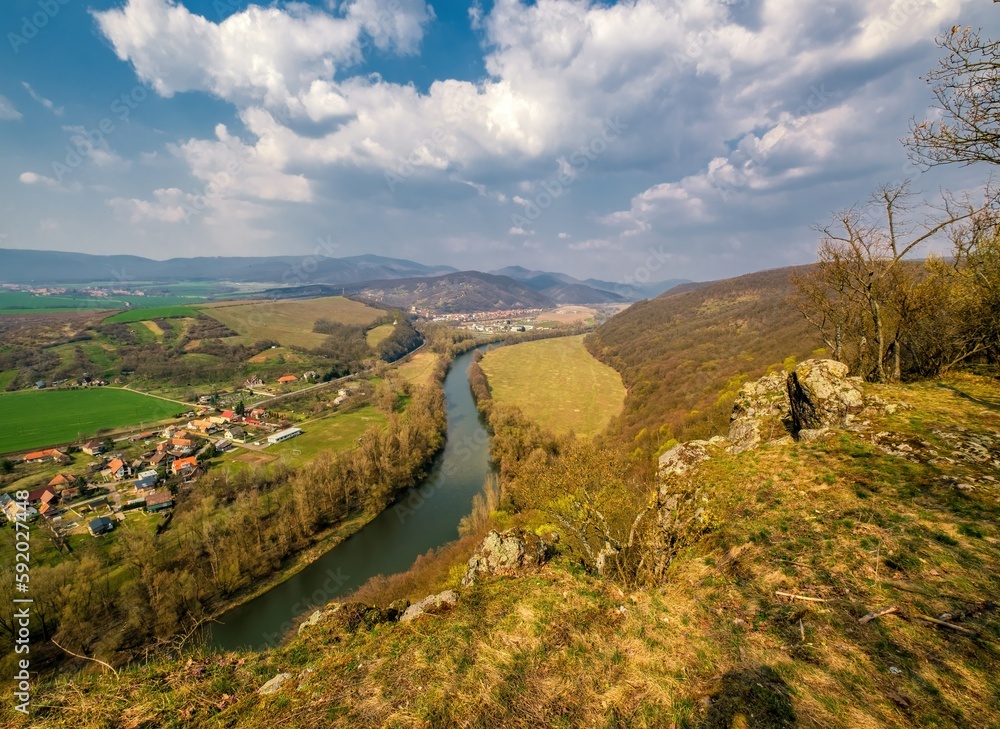 Naklejka premium winding Hron River makes its way through early spring rural farmland in the warm sunset sunlight.