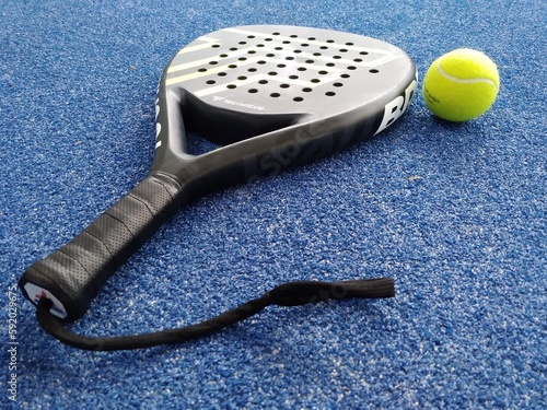 racket or shovel to play sports Padel tennis with a ball next to it on the court floor