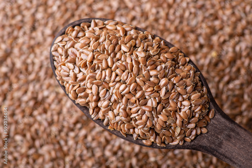 Linen grain in wooden spoon close up. Healthy food for stomach, cooking with linen grain Linen grain in wooden spoon close up. Healthy food for stomach, cooking with linen grain