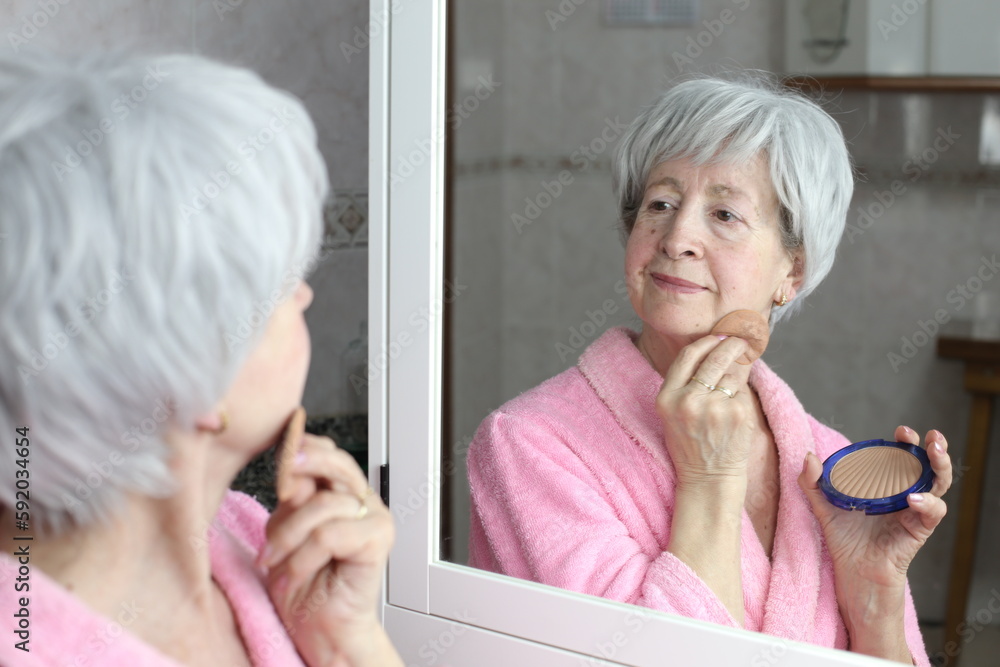 Senior woman applying make up with a sponge 