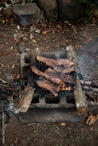 Several pork ribs on a handmade block and log spit. Outdoor barbecue