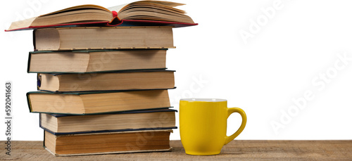 Stack of books by yellow mug on wooden table