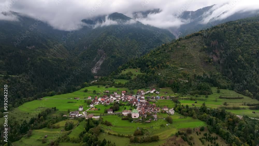 OVARO MIONE, ITALY - APRIL, 2023: Aerial drone view of a valley in the morning with clouds. Small mauntain village Mione with beautiful houses on the green slopes of the Italian Alps. OVARO MIONE, ITALY - APRIL, 2023: Aerial drone view of a valley in the morning with clouds. Small mauntain village Mione with beautiful houses on the green slopes of the Italian Alps.