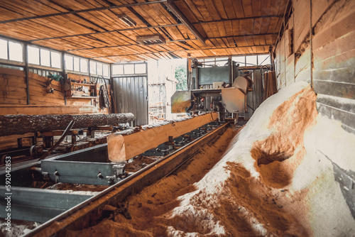 Sawmill. Process of machining logs in equipment sawmill machine saw saws the tree trunk on the plank boards. Wood sawdust work sawing timber wood wooden woodworking photo